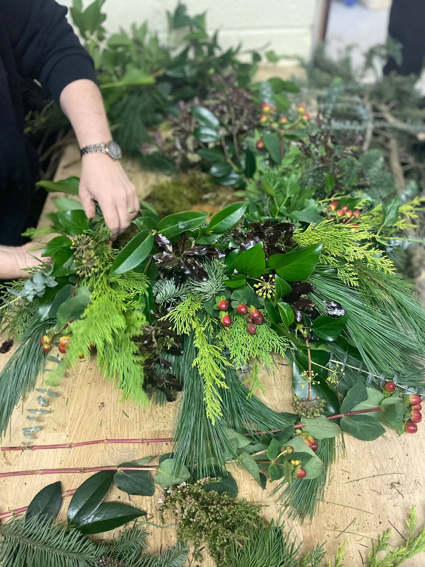 Person arranging greenery for a christmas wreath