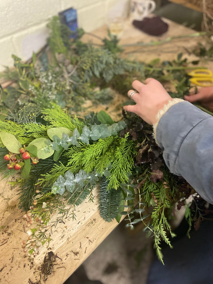 Person arranging greenery on a table with a focus on hands and plants.